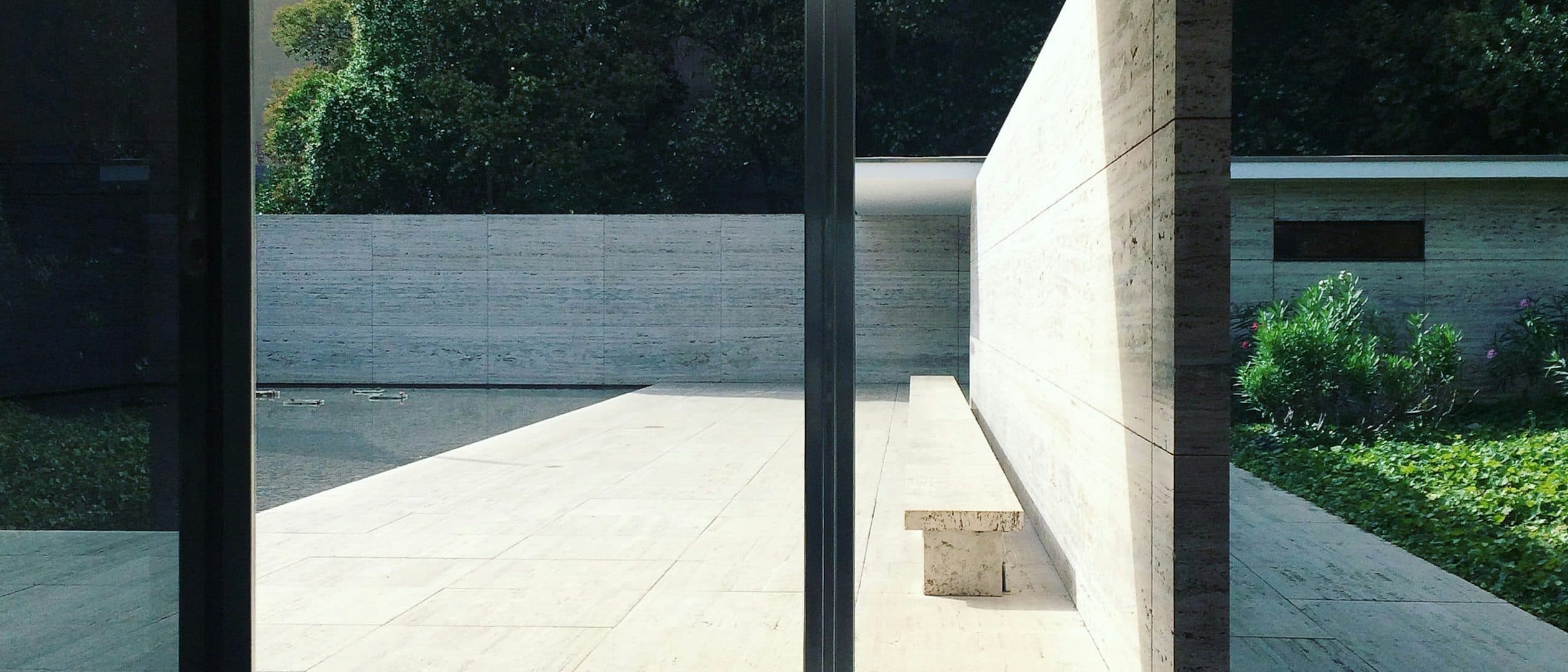 The villa seen along its length, deep eaves cutting a hard shadow across the terrace.