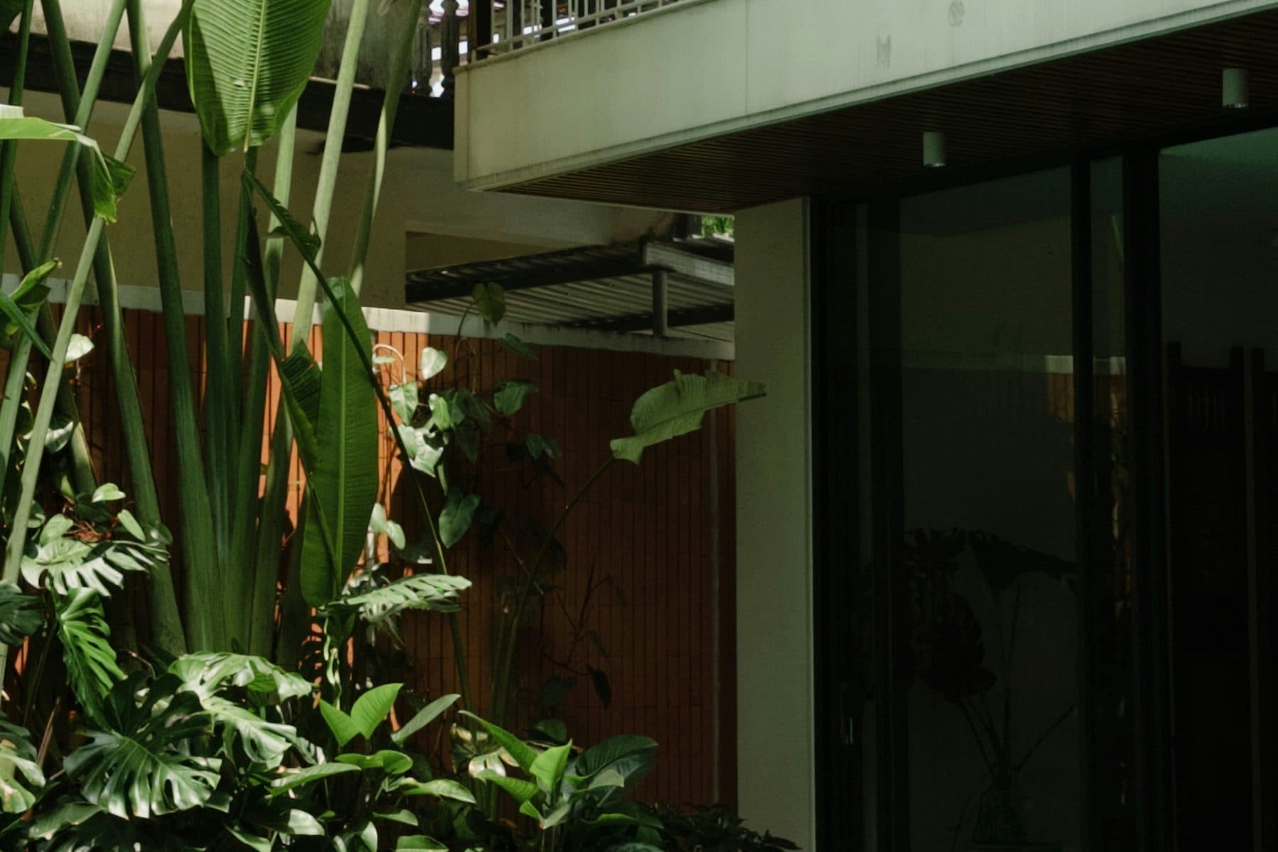 The covered terrace from the end of the pool, deep shadow under the eaves.