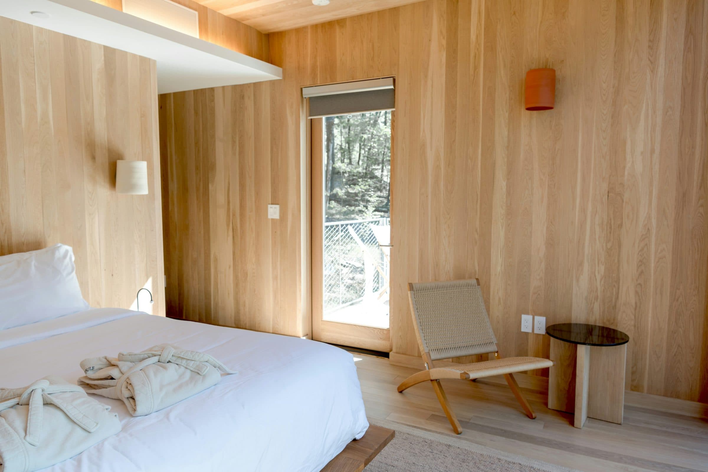 The guest bedroom at the back of the plan, queen bed and a desk under a high window.