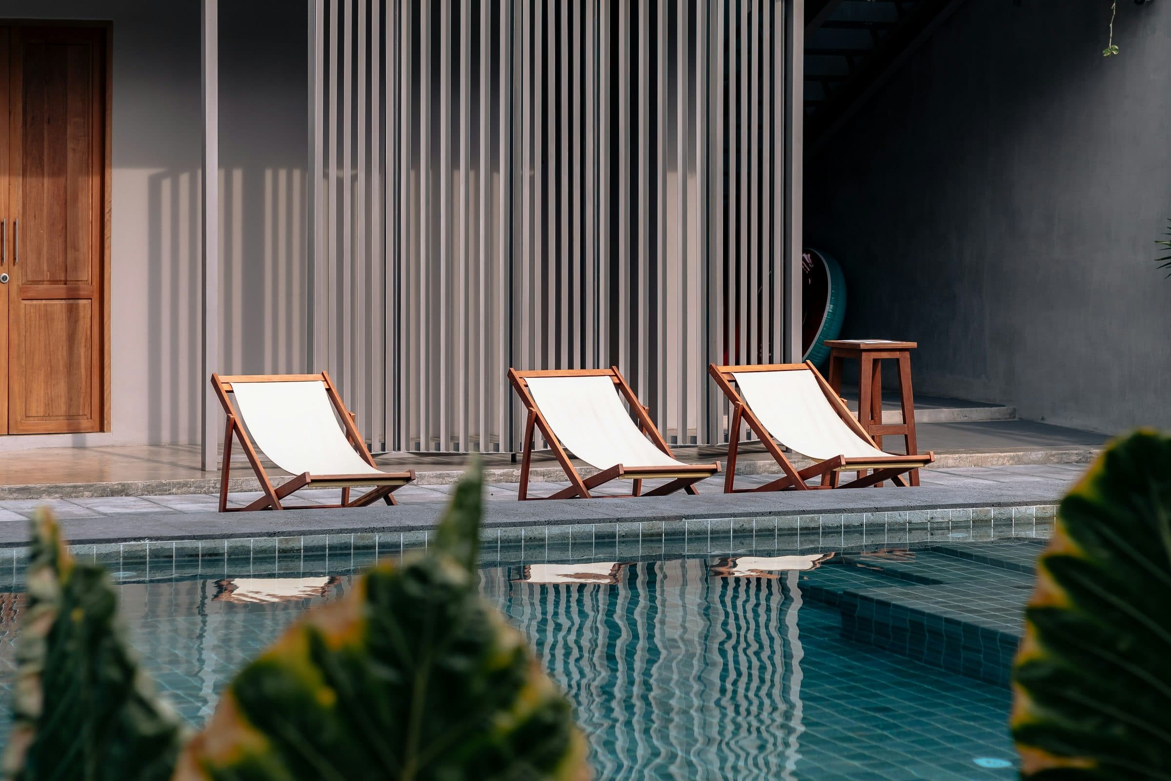 Two loungers in the shade of the terrace, the pool bright beyond them.