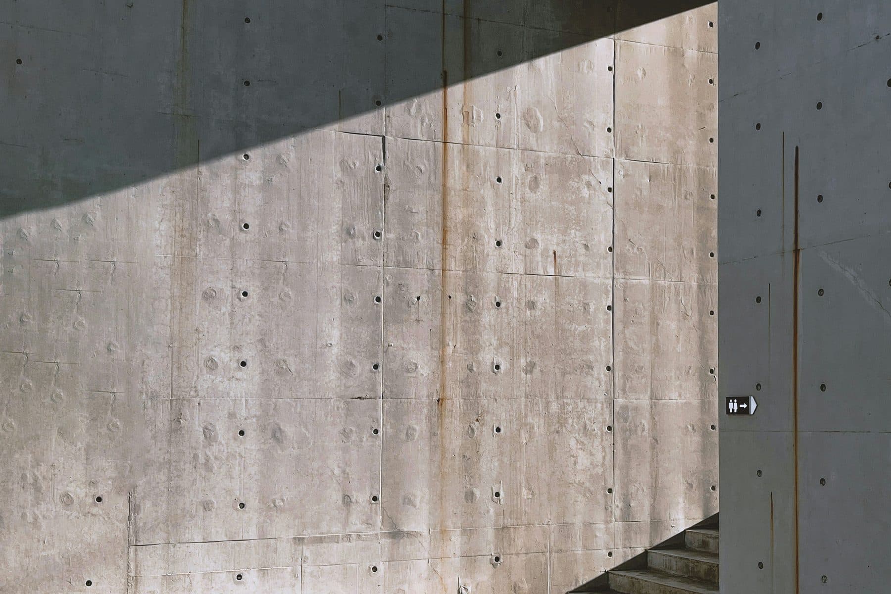 Low evening light raking across the concrete wall above the pool.